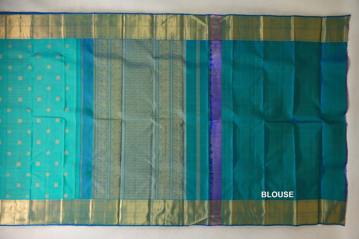 Aqua green Kanjivaram silk saree laid flat, showing a dotted body, patterned zari pallu, broad gold borders and matching blouse fabric.