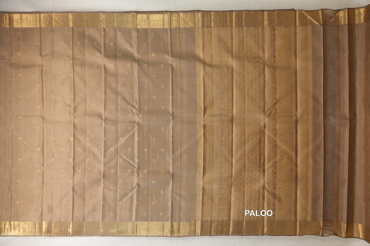 Greenish beige vintage Kanjivaram silk saree laid out, with small gold dots, gold borders and a patterned pallu on the right.
