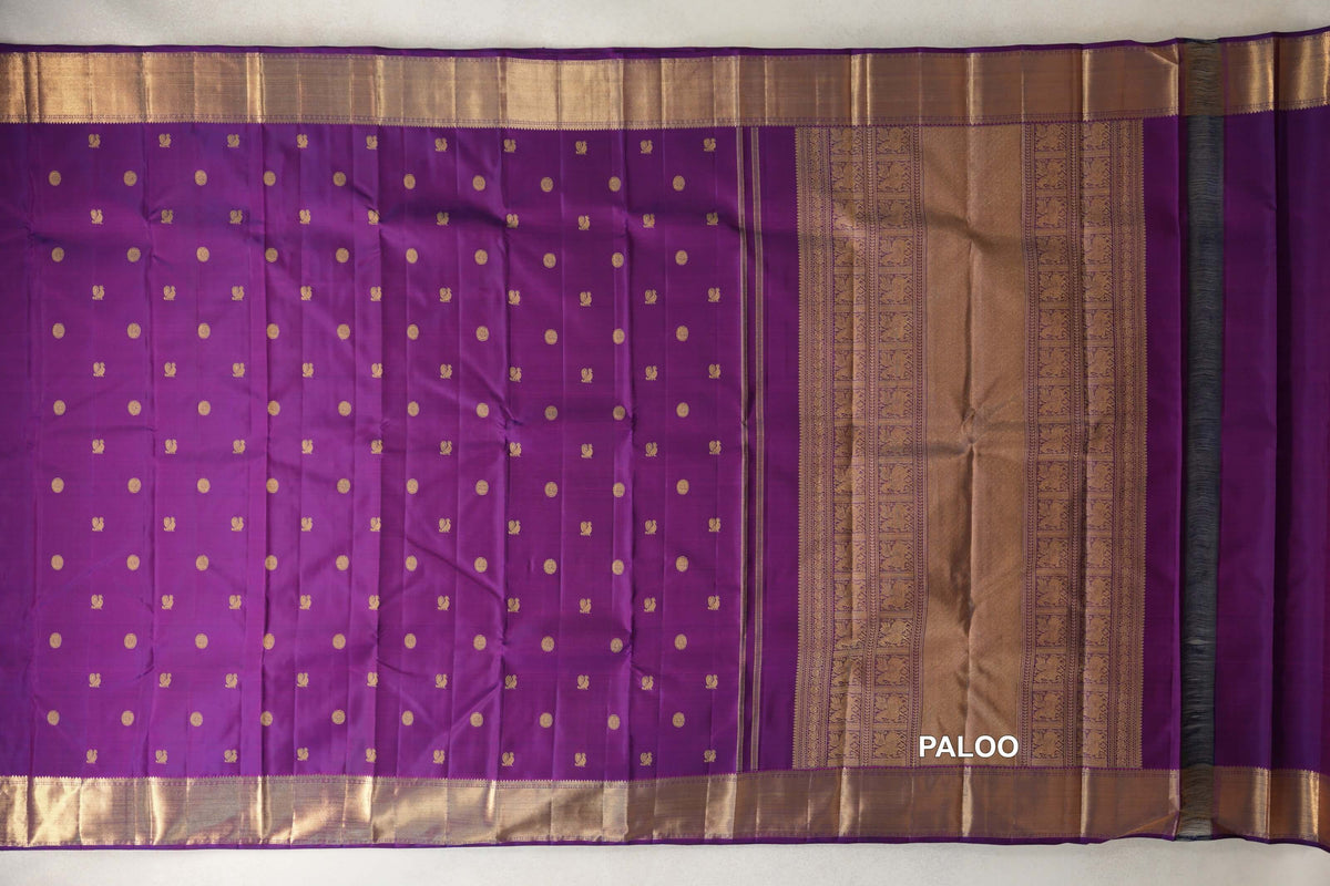 Purple Kanjivaram silk saree spread out, with rows of small gold motifs, wide gold borders and an ornate gold pallu.