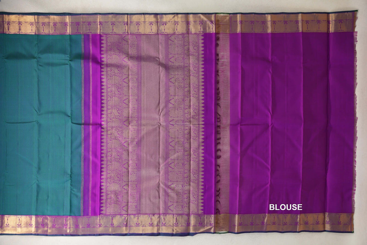 Kanjivaram silk saree laid open, showing a peacock green body, ornate purple pallu, purple blouse fabric and gold-toned borders with bottle green edges.