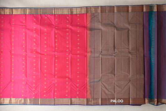 Lightweight Kanchipuram silk saree laid flat, with a bright rani pink body dotted in gold, teal blue borders and a finely patterned pallu.