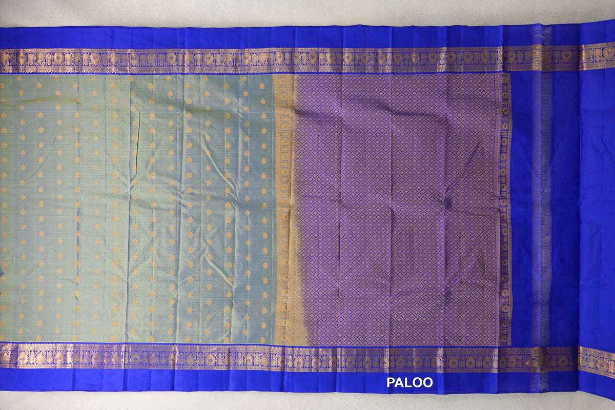 Spread-out lightweight Kanchipuram silk saree with a yellowish green body, small gold motifs, royal blue borders and a lattice-patterned pallu.