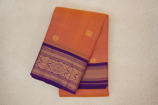 Folded lightweight Kanchipuram silk saree with a pink and yellow body, small gold motifs and an ornate gold-patterned deep purple border.