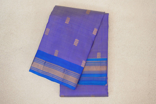 Folded lavender lightweight Kanchipuram silk saree with scattered gold geometric motifs and a royal blue border with gold stripes.