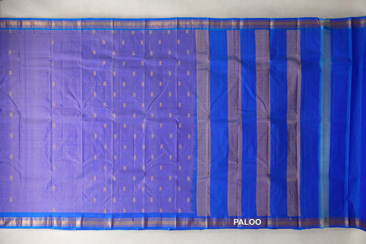 Lightweight Kanchipuram silk saree spread flat, with a lavender body dotted with gold motifs, royal blue borders and a pallu with gold patterned bands.