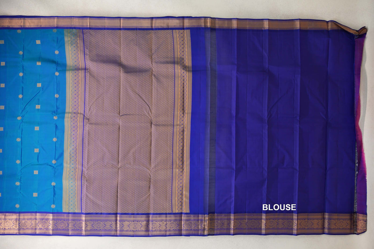 Lightweight Kanchipuram silk saree laid out with a peacock blue body, gold lattice pallu, deep blue violet blouse piece and patterned borders.