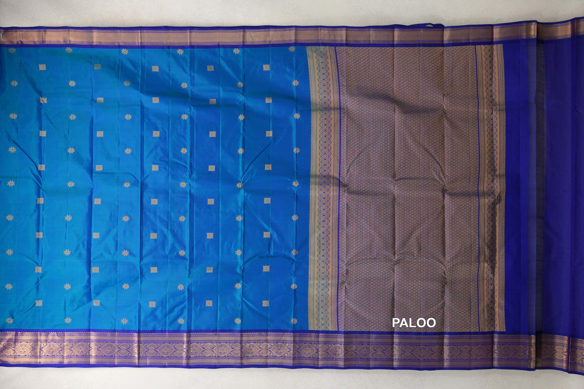 Unfolded Kanchipuram silk saree with a peacock blue body, small gold motifs, deep blue violet borders and a lattice-patterned pallu.