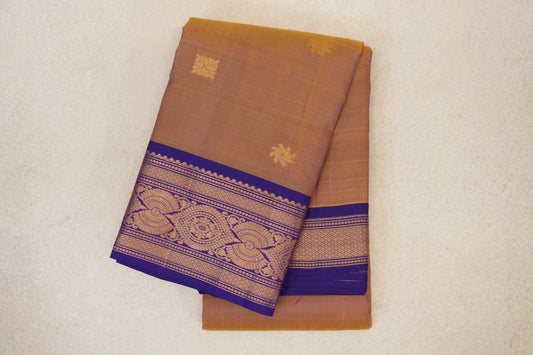 Folded lightweight Kanchipuram silk saree in mustard, with small gold motifs and a violet purple border woven with ornate gold patterns.