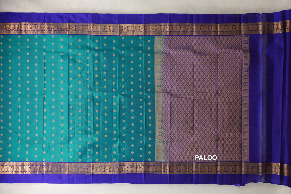 Lightweight Kanchipuram silk saree laid flat, with a peacock green body of small gold motifs, deep royal blue borders and a gold lattice pallu.