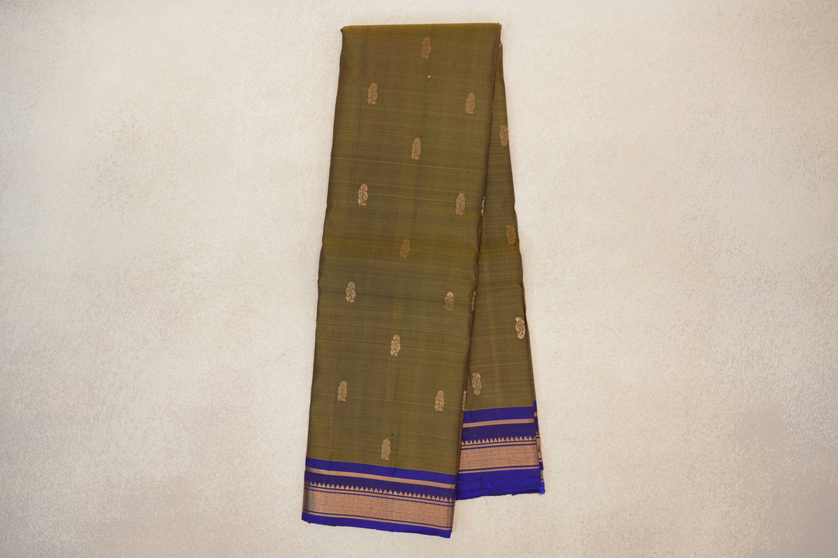 Folded olive green Kanchipuram silk saree with scattered gold motifs and deep royal blue borders featuring gold geometric detailing.