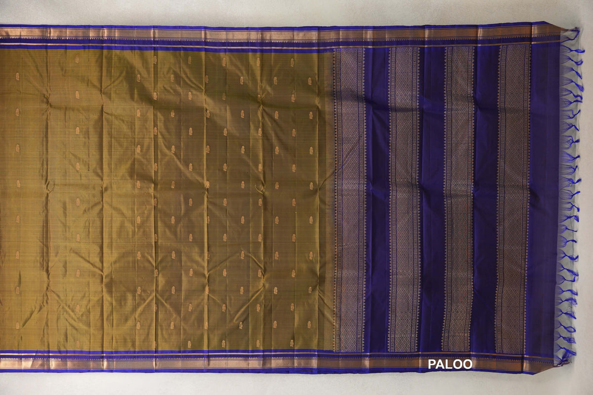 Unfolded olive green Kanchipuram silk saree with small gold-toned motifs, deep royal blue borders and a patterned blue pallu with tassels.