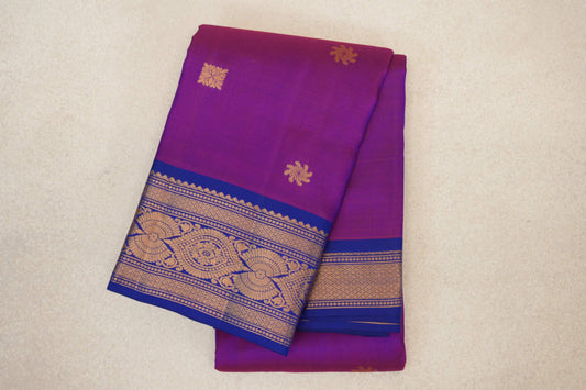 Folded lightweight Kanchipuram silk saree with a rani pink body, scattered gold floral motifs and an ornate deep royal blue border.