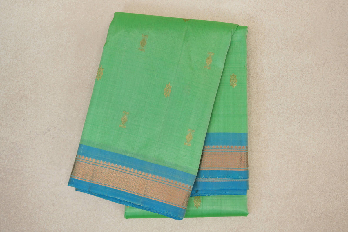 Folded mint green Kanchipuram silk saree with small gold motifs and light turquoise blue borders woven with gold geometric patterns.
