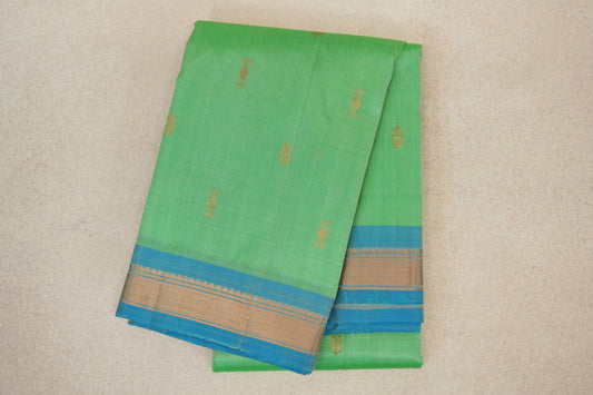 Folded mint green Kanchipuram silk saree with small gold motifs and light turquoise blue borders woven with gold geometric patterns.