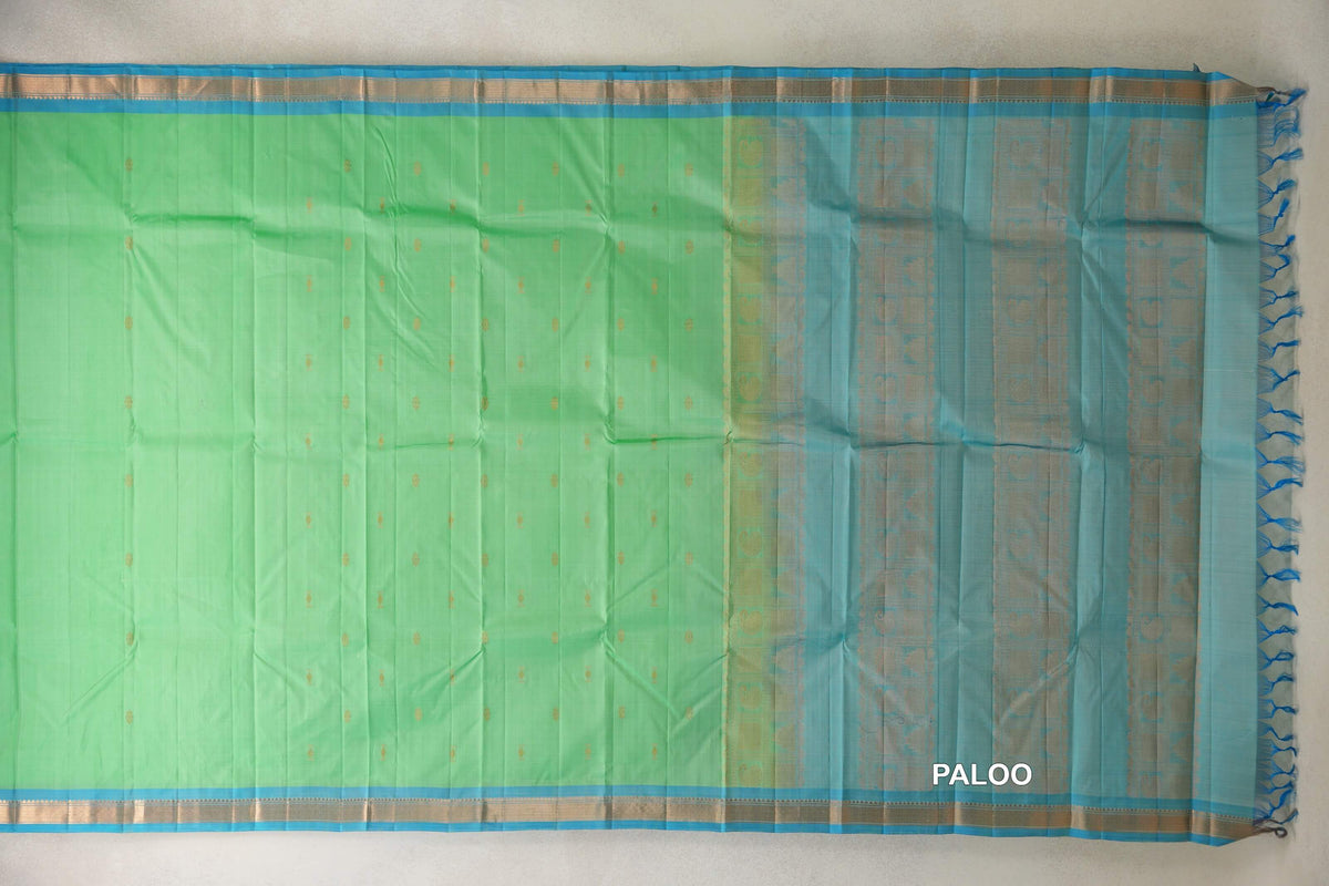 Lightweight Kanchipuram silk saree laid flat, with a mint green body dotted with gold motifs, light turquoise blue borders and a patterned pallu with tassels.