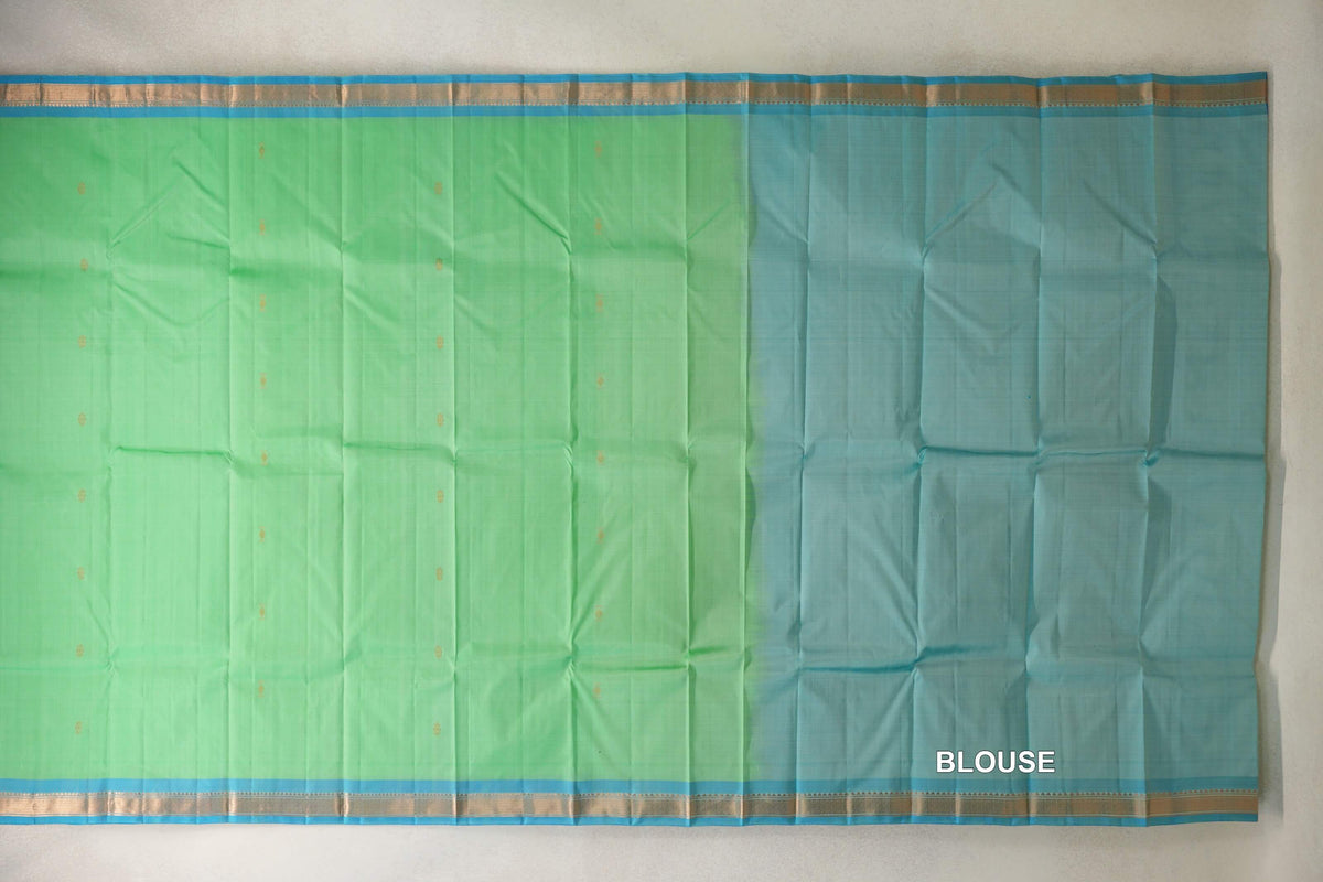 Lightweight Kanchipuram silk saree spread flat, with a mint green body, small gold motifs, turquoise blue borders and a matching blouse panel on the right.