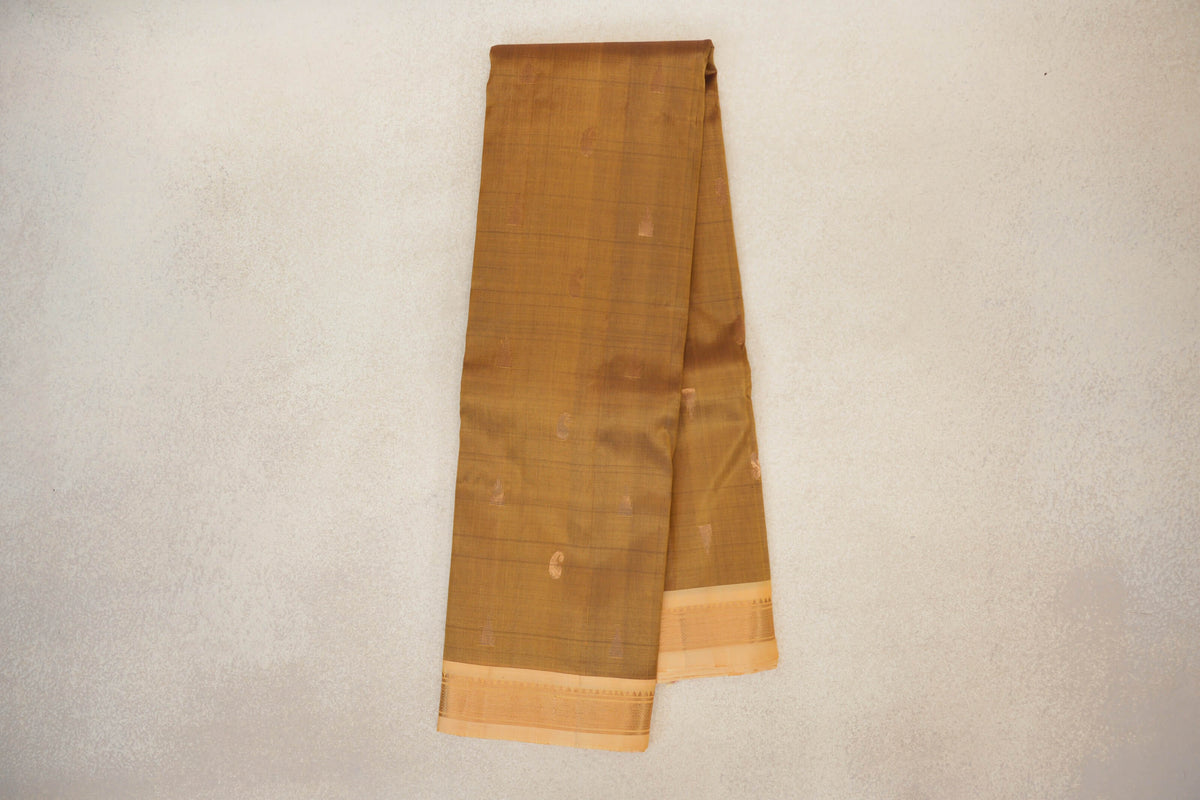 Folded oil mustard lightweight Kanchipuram silk saree with small woven accents and a sandal border with fine patterned bands.