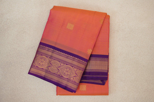 Folded pink and yellow Kanchipuram silk saree with small gold motifs and a violet purple border woven with gold floral and geometric patterns.