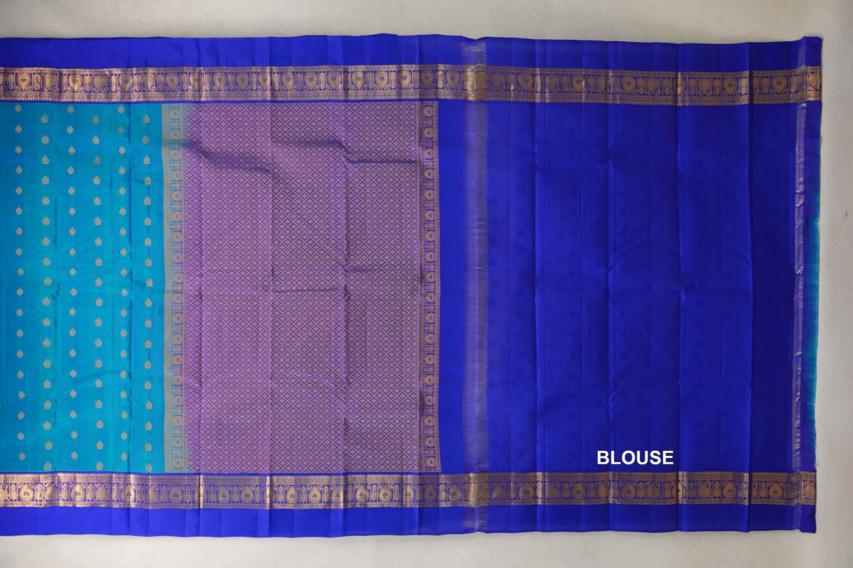 Lightweight Kanchipuram silk saree laid flat, with a peacock blue motif-dotted body, a lattice-patterned pallu, royal blue blouse panel and gold-patterned borders.