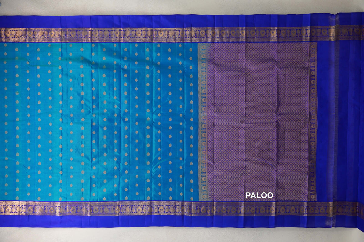 Light Weight Kanchipuram silk saree laid out, with a peacock blue body dotted in gold, royal blue patterned borders and a gold lattice pallu.