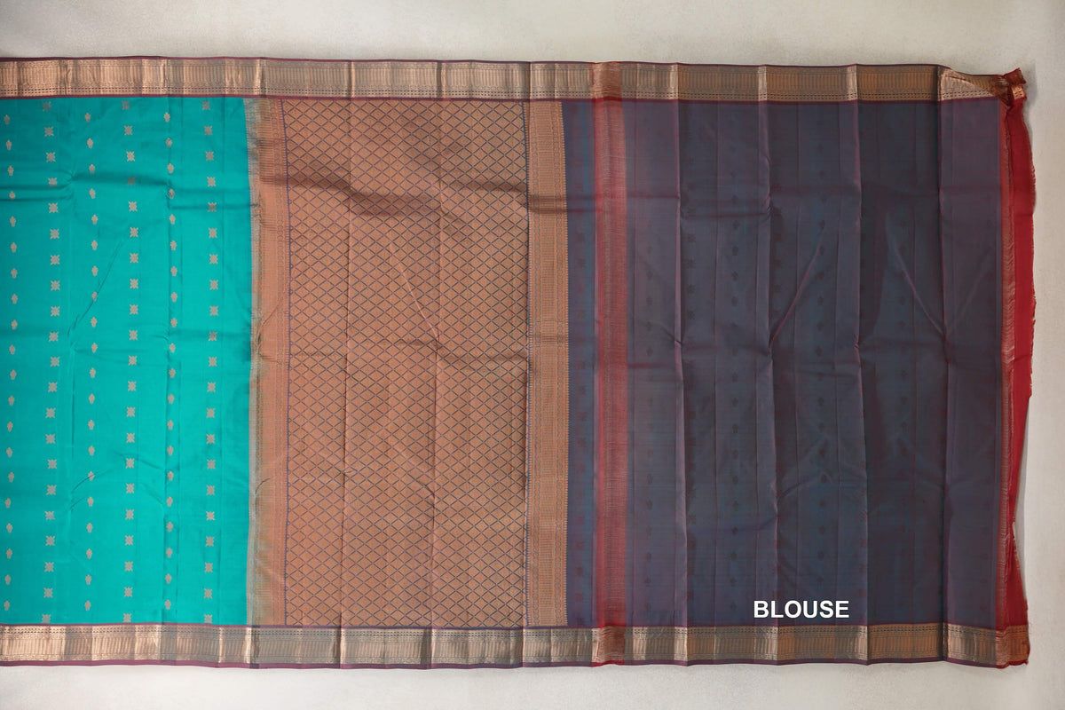 Kanchipuram silk saree laid flat, with a peacock green patterned body, gold-toned lattice pallu, maroon-green borders and blouse fabric at right.