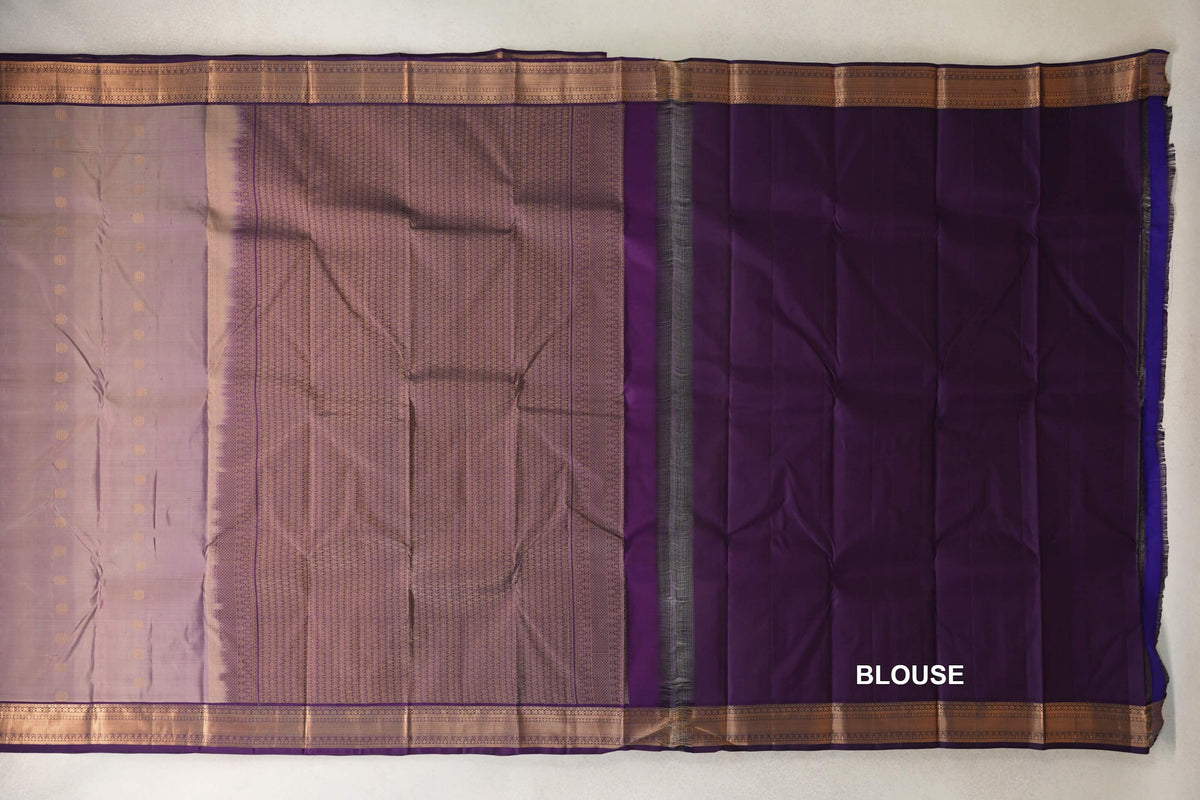 Light weight Kanchipuram silk saree laid open, showing a beige and purple dotted body, patterned pallu, deep purple blouse fabric and gold borders.