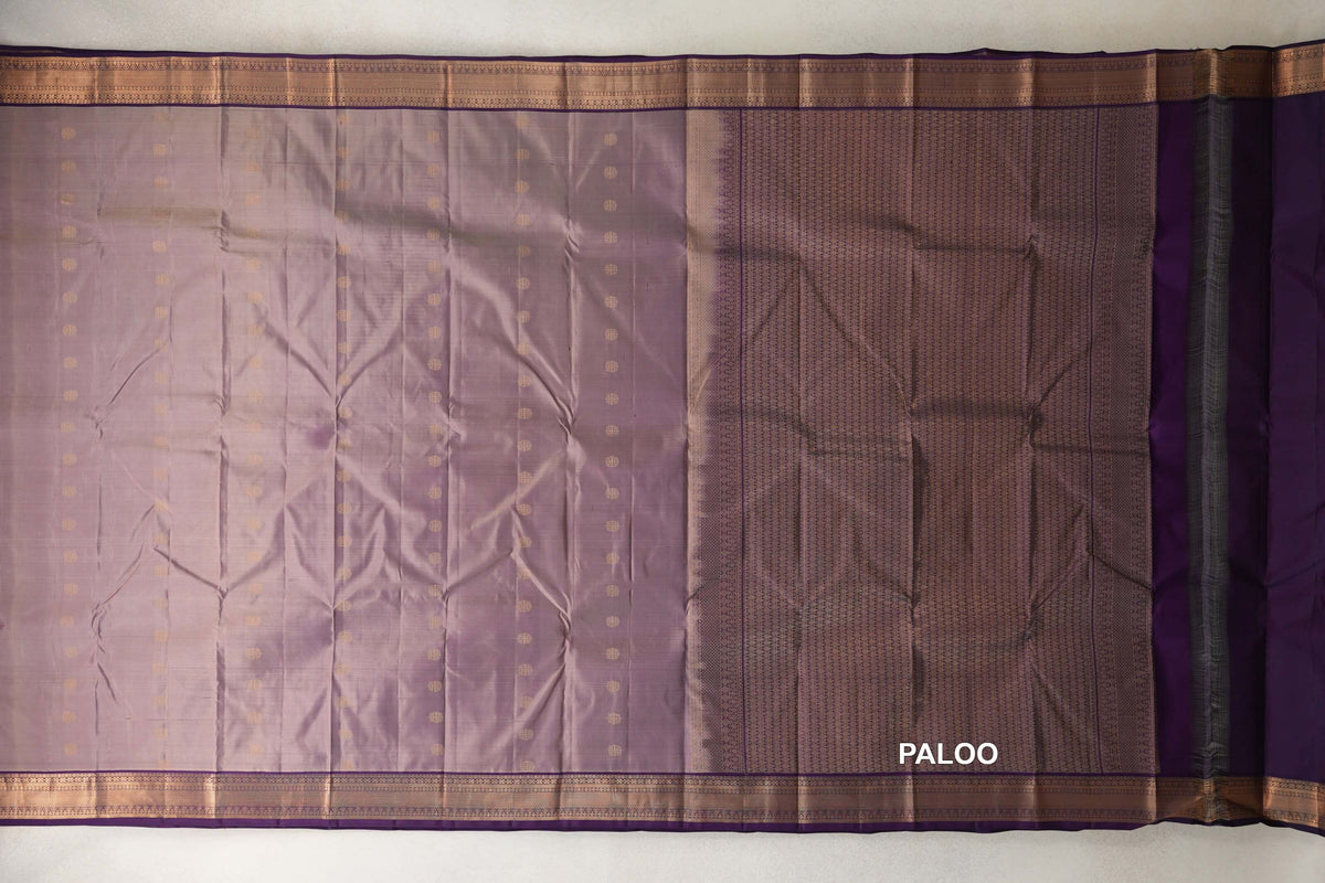 Lightweight Kanchipuram silk saree spread flat, with a beige and purple dotted body, deep purple borders and a densely patterned pallu on the right.
