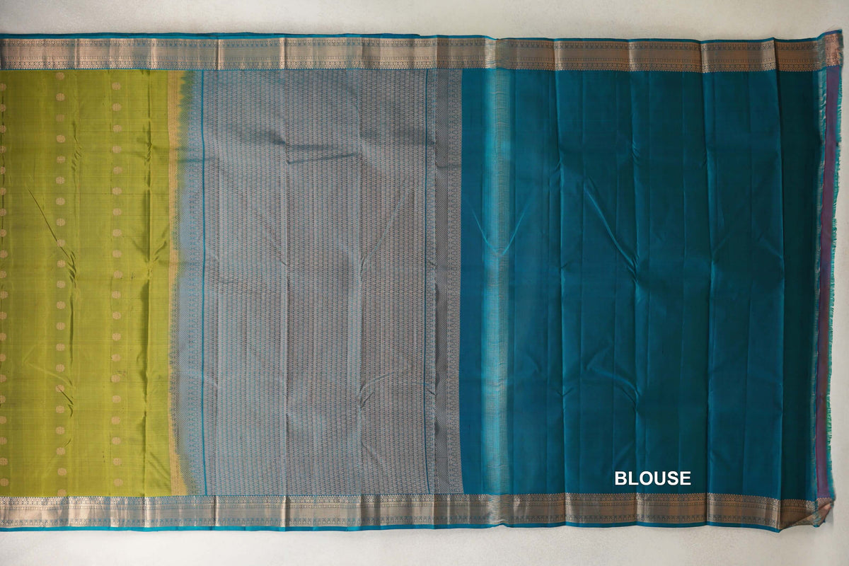 Unfolded olive green Kanchipuram silk saree with gold dots, a patterned teal blue pallu, metallic borders and a plain teal blue blouse piece.