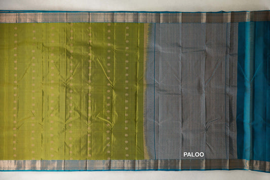 Olive Green Kanchipuram silk saree spread flat, with rows of small gold dots, teal blue woven borders and a densely patterned pallu.