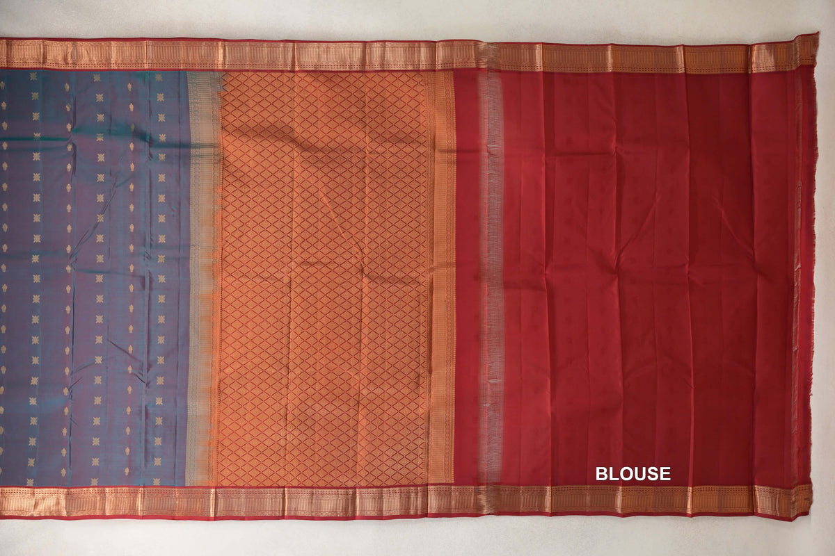 Laid-out Kanchipuram silk saree with a teal blue body dotted with gold motifs, a lattice-patterned pallu, deep red blouse fabric and ornate borders.