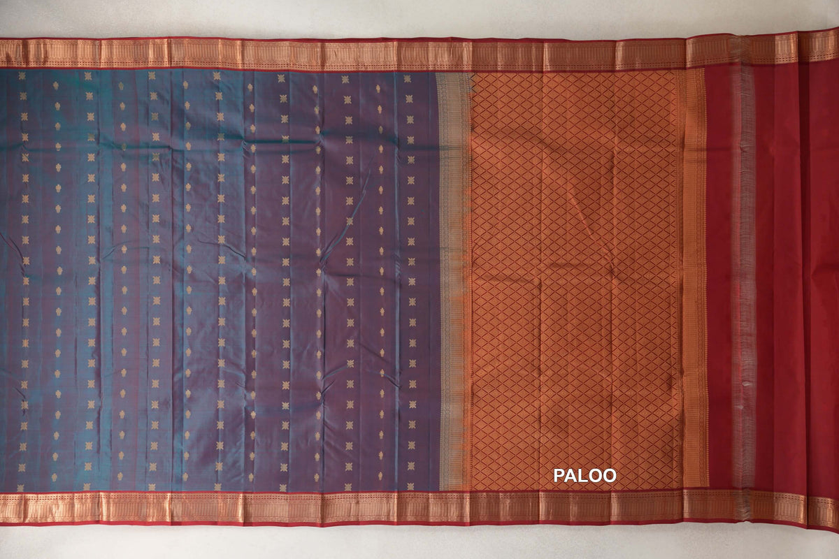 Kanchipuram silk saree laid out with a teal blue and red body dotted with small gold motifs, deep red borders and a lattice-patterned pallu.