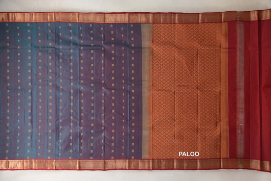 Kanchipuram silk saree laid out with a teal blue and red body dotted with small gold motifs, deep red borders and a lattice-patterned pallu.