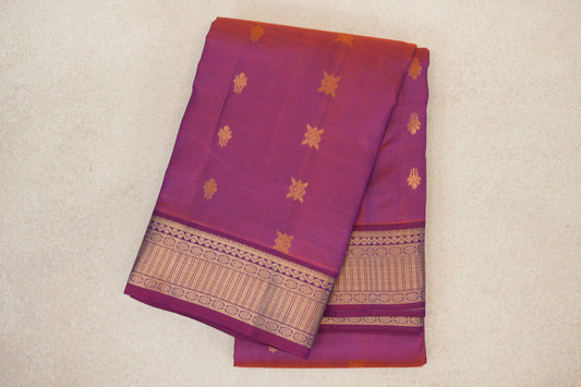 Folded blue and red light weight Kanchipuram silk saree with scattered gold motifs and a wide patterned gold zari border.