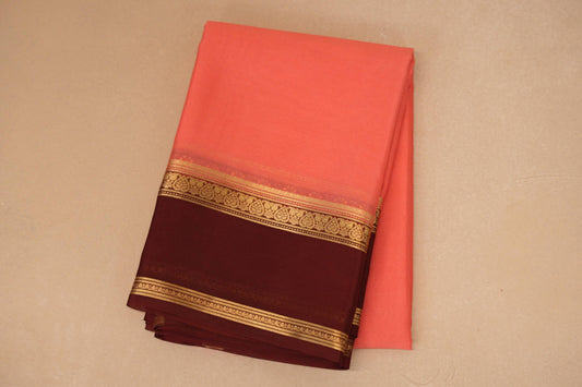 Folded saree with a pink and maroon design on a beige background