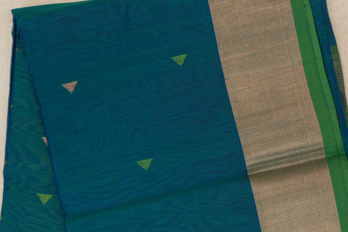 Folded peacock blue Maheshwari silk cotton saree with small green and beige triangular motifs, a broad beige border and parrot green selvedge.