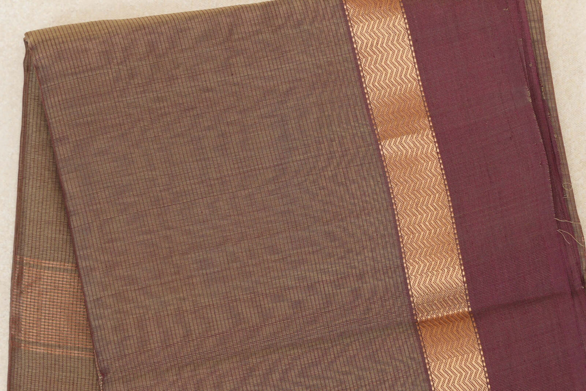 Folded Maheshwari silk cotton saree showing a finely lined beige and magenta body, a gold-toned zigzag band and a wide magenta border.