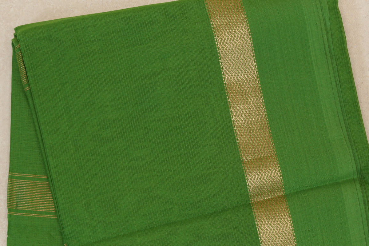 Folded leaf green Maheshwari silk cotton saree with a finely textured body, a gold-toned wavy border and narrow stripes along one edge.