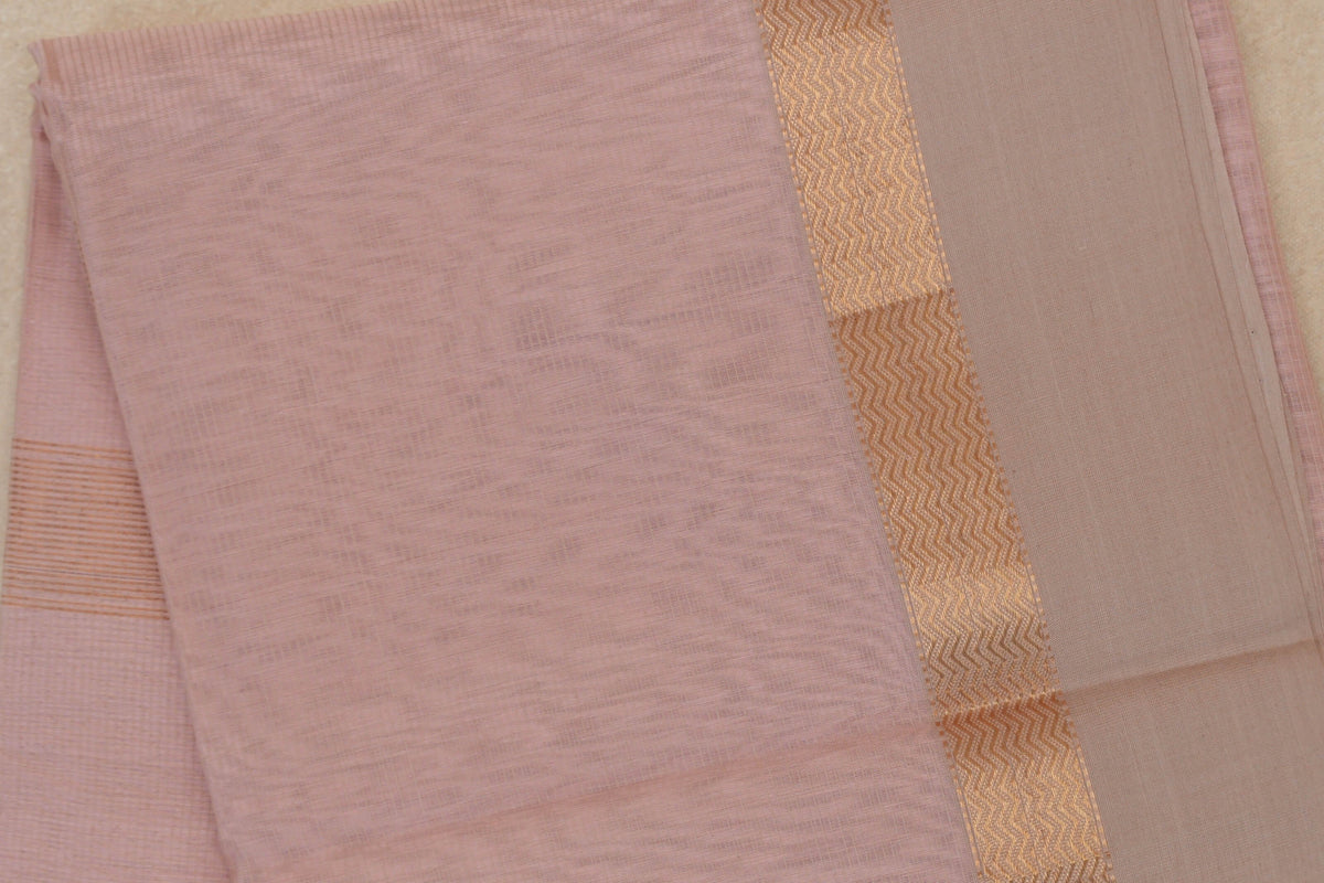 Folded blush pink Maheshwari silk cotton saree showing a finely striped body and light sandal beige border with a shimmering zigzag band.