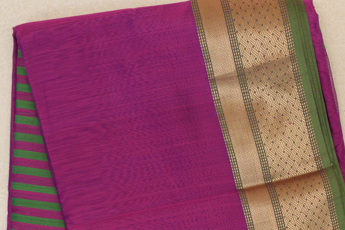 Folded Maheshwari silk cotton saree showing a dark magenta body, leaf green stripes on the pallu and a gold-patterned border with a green edge.