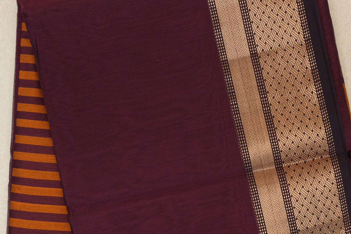 Close-up of a deep plum Maheshwari silk cotton saree, with a gold-toned geometric border and deep orange striped pallu peeking out.