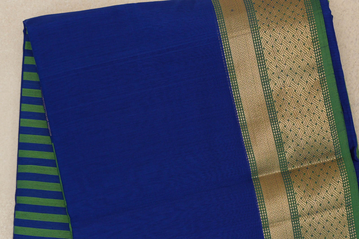 Folded bright royal blue Maheshwari silk cotton saree with leaf green stripes peeking out and a wide leaf green border with gold geometric patterning.