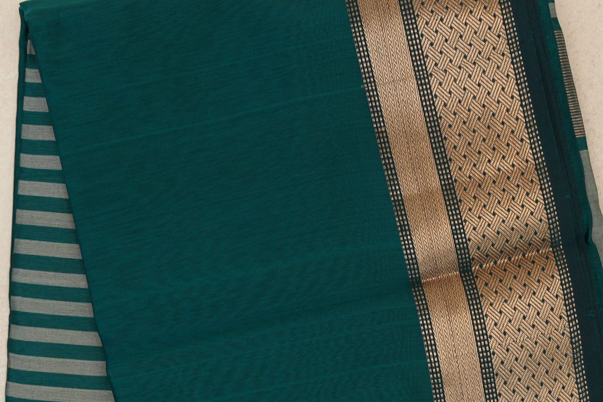 Folded peacock green Maheshwari silk cotton saree with a patterned dark peacock green border and silver grey stripes peeking out at left.