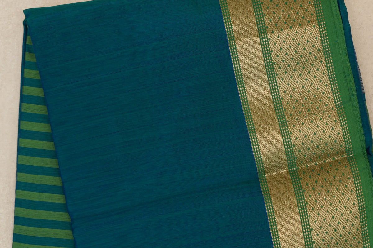Folded peacock green silk cotton saree with a patterned leaf green border and a glimpse of the striped pallu.
