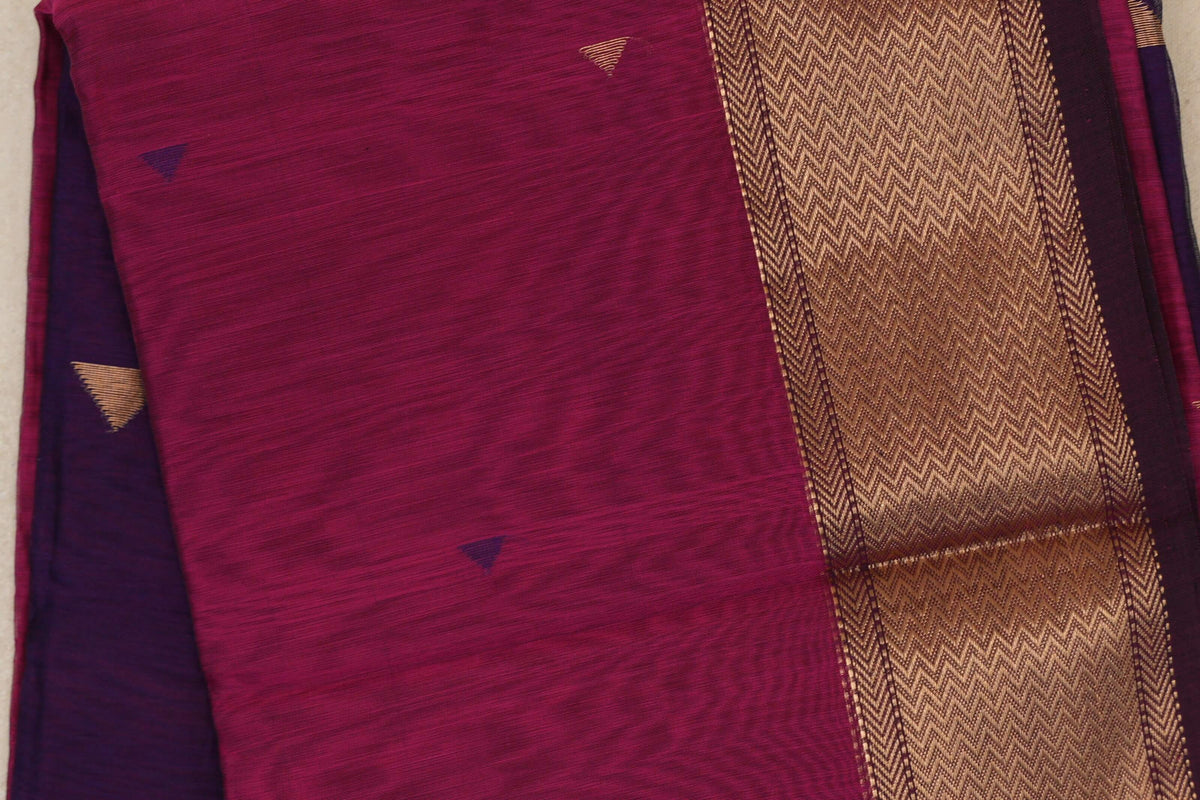 Close-up of a folded Deep Rani Pink Maheshwari silk cotton saree with small triangular accents, a gold chevron border and Deep Purple fabric at the side.