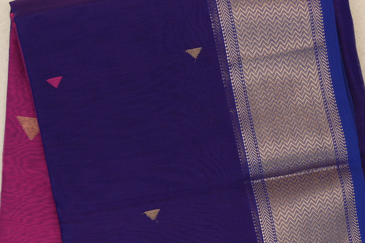 Folded deep violet Maheshwari silk cotton saree with small triangle motifs, a gold chevron-patterned border and deep rani pink fabric peeking out.