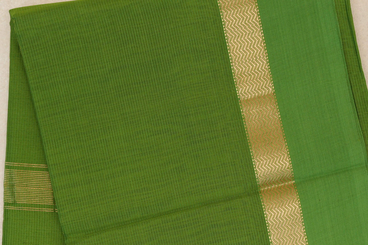 Folded leaf green Maheshwari silk cotton saree with fine pinstripes, a gold zigzag border and a glimpse of a striped end.