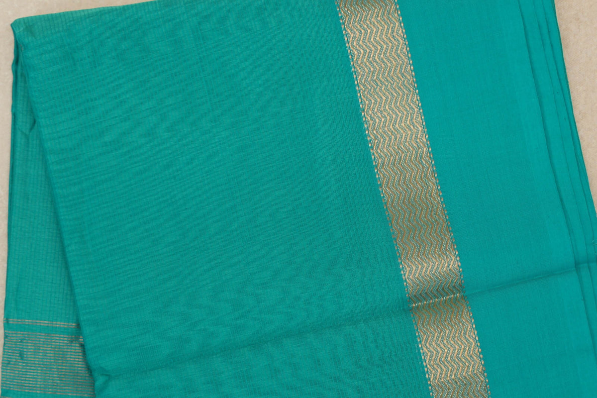 Folded bright aqua green Maheshwari silk-cotton saree showing a subtly textured body, gold-toned zigzag border and fine stripes.