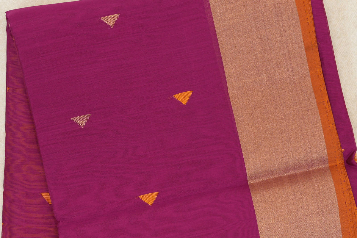 Folded deep magenta Maheshwari silk cotton saree with small orange striped triangles and a broad gold-toned border edged in orange.