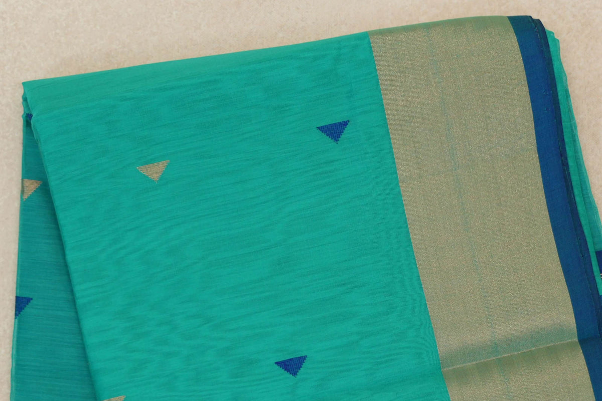 Folded sea green Maheshwari silk cotton saree with scattered blue and light gold triangles, a broad light gold border and classic blue edge.