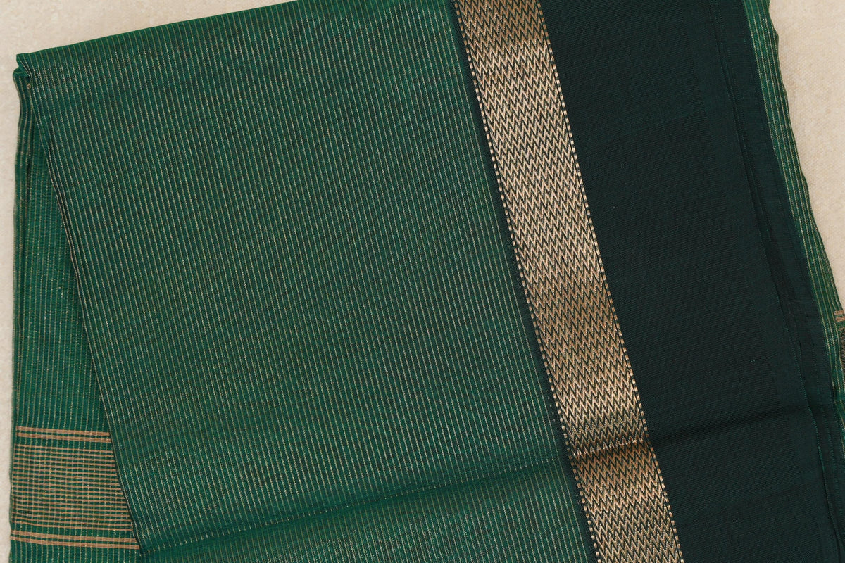 Folded bottle green Maheshwari silk cotton saree with fine gold-toned stripes, a patterned band and a dark bottle green border.